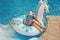 Cute adorable girl in sunglasses with drink lying on inflatable ring unicorn. Kid child enjoying having fun relaxing resting in