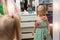 Cute adorable hesitating blond caucasian little girl trying on fashion mint dress at children fashion sewing studio and
