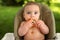 Cute adorable infant funny dirty baby trying to eat himself with fruit or vegetable puree smeared on his face. Baby