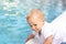 Cute adorable little caucasian blond smiling todller boy kid treing water temperature pool edge before swimming. Happy