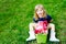 Cute adorable little toddler girl with lot of pink peony flowers in bucket. Happy smiling child in domestic garden on