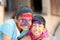 Cute adorable siblings playing with colours during holi festival of colors Indian asian caucasian creative portrait