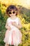 Cute adorable stylish Caucasian child in pink dress and yellow sunglasses