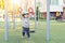 Cute adorable toddler boy enjoy swinging using gymnastic rings at sport playground on residential apartment building outdoors.