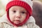 Cute adorable white Caucasian smiling baby girl boy with large brown eyes in red knitted hat