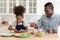 Cute african american girl enjoying cooking with father in kitchen.