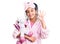 Cute african american girl wearing sleep mask and pajama holding pink teddy unicorn doing ok sign with fingers, smiling friendly