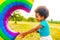 cute african american little girl with curly afro hair playing rainbow balloon outdoors