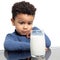 Cute afro american boy staring at glass of milk at table