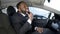 Cute Afro-American businessman looking in rear-view car mirror and smiling