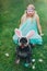 Cute Airedale Terrier dog in Easter bunny ears and little girl in bunny mask on Easter day sitting on grass in garden.