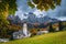 Cute alpine village with traditional mountain church, Dolomites, Colfosco, Italy