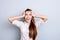 Cute amazed girl in white shirt, holding her head, she is shocked, extremely happy, with wide open eyes and mouth on pure grey ba