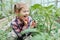 Cute amazing adorable Caucasian girl looking at plants grass in greenhouse through magnifying glass.