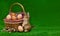 Cute artificial easter bunny sitting on the grass near eggs, a basket and willow twigs on a green background on the left