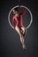 Cute artistic gymnast exercising with hanging hoop