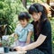 Cute asian child girl helping mother planting or cutivate the plants. Mom and daughter engaging in gardening at home. Happy activi