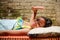 Cute Asian ethnicity little girl lying down on a bench, sunbathing in the morning at home