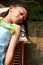 Cute Asian ethnicity little girl lying down on a bench, sunbathing in the morning at home