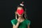 cute asian girl child dressed in a green dress holding a Christmas ornament and a heart stick on a black background