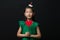 Cute asian girl child dressed in a green dress holding a Christmas ornament and a heart stick on a black background