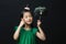 Cute asian girl child dressed in a green dress holding an idea bulb stick with a christmas head decoration on a black background.