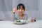 Cute Asian girl drinking a glass of milk in the morning before going to school. Little girl eats healthy vegetables and milk for