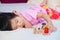 Cute Asian girl is lying on a soft white mattress. Child play wooden toys, train number figures happily.
