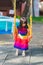 Cute Asian girl playing on yellow swing. Child are agile playing in playground. The 4 year old is dressed in bright colors.
