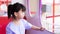 Cute Asian girl is riding on carousel in amusement park after returning from school.