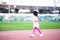 Cute Asian girl running happily. Child look sideways. Kid was wearing pink T-shirt and leggings, wearing white sneakers.