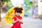 Cute Asian kid wearing red cheongsam. Child standing with yellow vintage umbrella looking at camera with sweet smile.