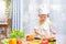 Cute Asian little boy child wearing chef hat and apron having fun preparing, cooking healthy food in kitchen, Fun indoor