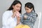 Cute Asian little girl learning how to brush her teeth and gums on a jaw model from young Indian dentist with toothbrush at