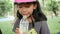 Cute Asian little girl wearing pink helmet drinking water with happiness at nature park