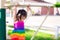 Cute Asian little kid girl are wearing colorful clothes hanging on the bars with both hands. Child looked down at the floor.