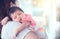 Cute asian newborn baby girl resting on mother`s shoulder