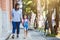 Cute asian pupil girl with backpack holding her mother hand and going to school