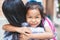 Cute asian pupil girl with backpack hugging her mother with happiness after back from school