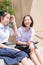 Cute Asian Thai high schoolgirls student couple in school uniform sit on the stairway chatting with a happy smiling and laughing