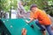 Cute Asian toddler boy having fun trying to climb on artificial boulders at playground on nature