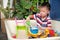 Cute Asian toddler boy playing with sand alone at home, Child playing with toy construction machinery, Montessori education,