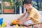 Cute Asian young boy playing with sand alone Kid playing with sand toys in urban home garden , Montessori education, Creative play