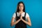 Cute asian young girl praying over blue background. Woman in glasses begging someone.