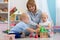 Cute babies play with carer in nursery or kindergarten