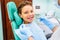 A cute baby is being examined by a professional pediatric dentist. Very happy boy after the visiting of doctor at the clinic with