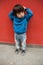 Cute baby in blue casual clothes standing in front of a red wall