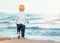 Cute baby boy on the beach, admiring the sea. Bare feet. Happy