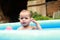 Cute baby boy in blue inflating pool playing with ball