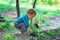 Cute baby boy digging in ground in spring forest